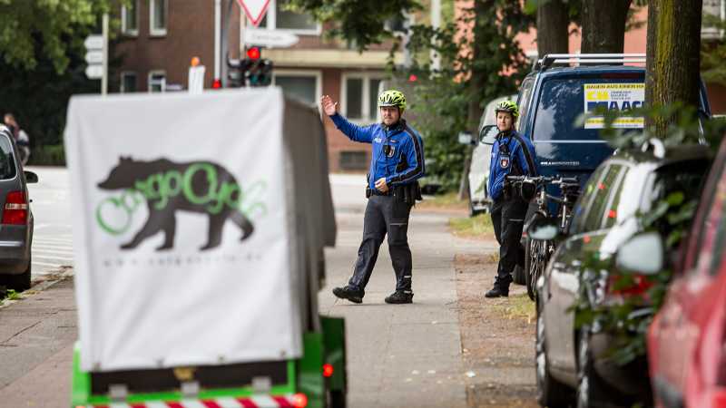 Die Fahrradpolizisten halten ein Lastenfahrrad an.