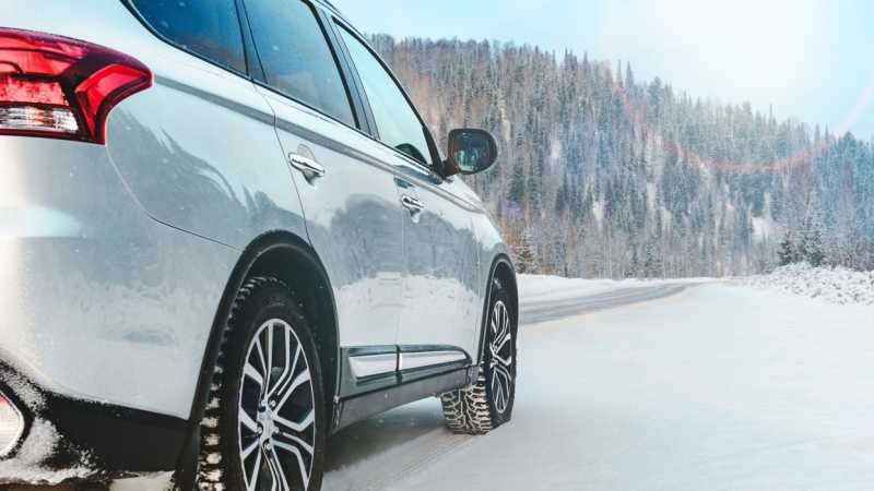 Ein weißer SUV ist auf einer verschneiten Bergstraße unterwegs