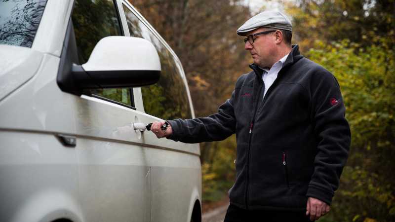 Das Bild zeigt Björn P. während er seinen weißen VW-Bus abschließt.