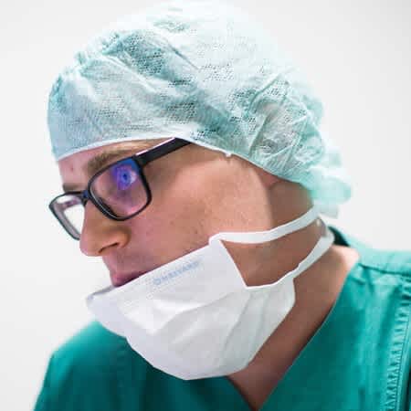 Der Arzt Florian Kunz trägt seine OP-Ausrüstung aus Maske und Haarnetz.