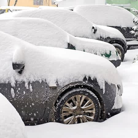 vier stark verschneite Autos stehen in einer Reihe.