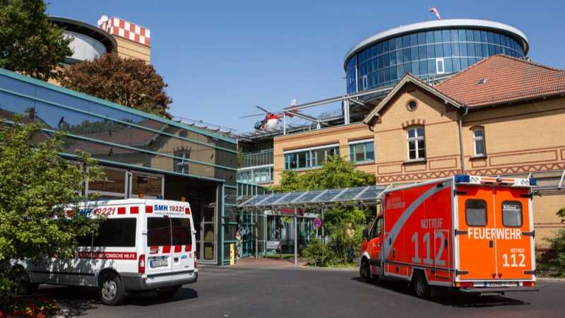 Das Bild zeigt die Krankenhauszufahrt zur Notaufnahme mit zwei davorstehenden Rettungsfahrzeugen.