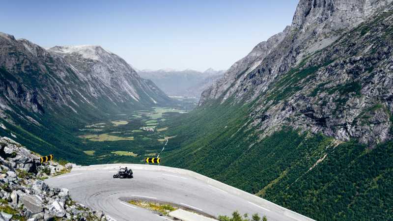 Vor einer Bergkulisse fährt Mike Dodd auf dem Motorrad um eine enge Kurve.