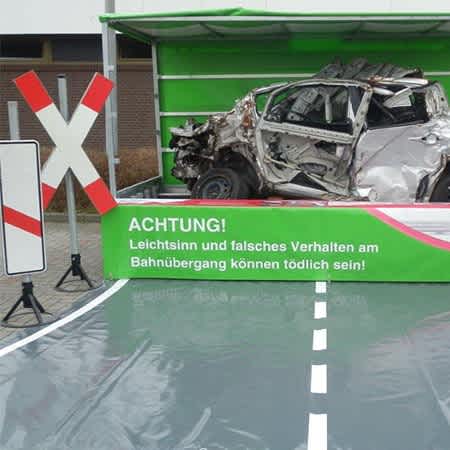 Ein verunfalltes Auto wird auf einem künstlichen Bahnübergang ausgestellt.