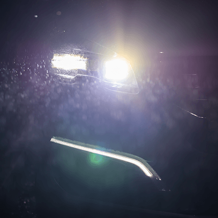 Man sieht leuchtende Autoscheinwerfer in der Dunkelheit.