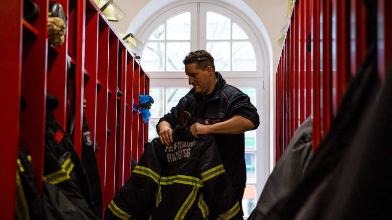 Das Bild zeigt einen Feuerwehrmann im Umkleideraum der Feuerwache.