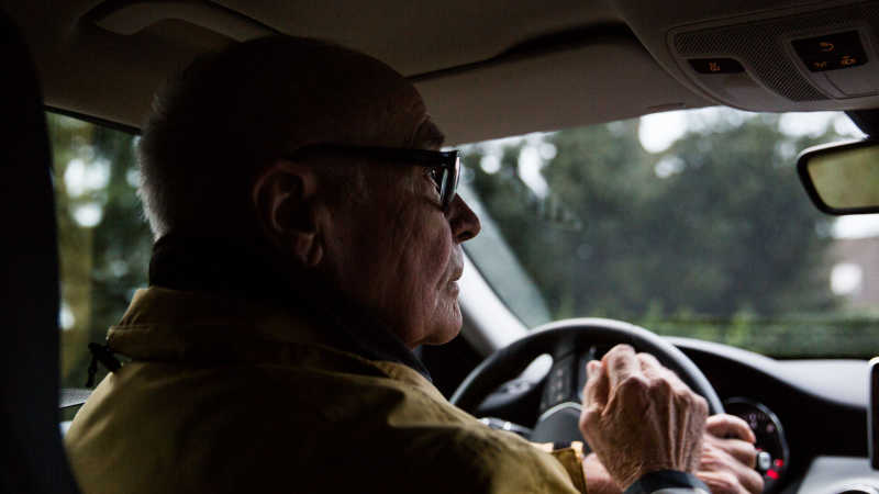 Opa Manfred sitzt am Steuer und fährt Auto.