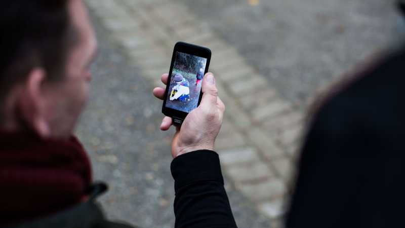 Ein Mann zeigt Bilder von Kindern auf einem Smartphone.