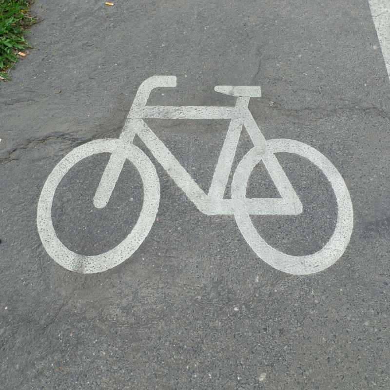 Ein weißes Fahrradsymbol auf dem Boden, das einen Radweg kennzeichnet.