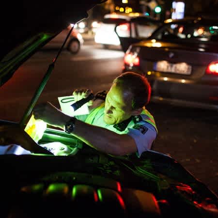 Der Polizist Rainer Fuchs überprüft ein Auto auf getunte Teile mit einer Taschenlampe.