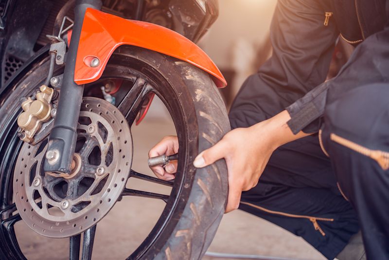 Ein Mechaniker prüft den Frontreifen eines Motorrads. 