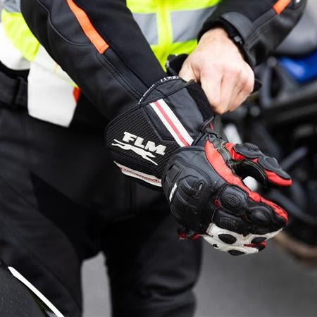 Mensch zieht sich seine Motorradhandschuhe an.