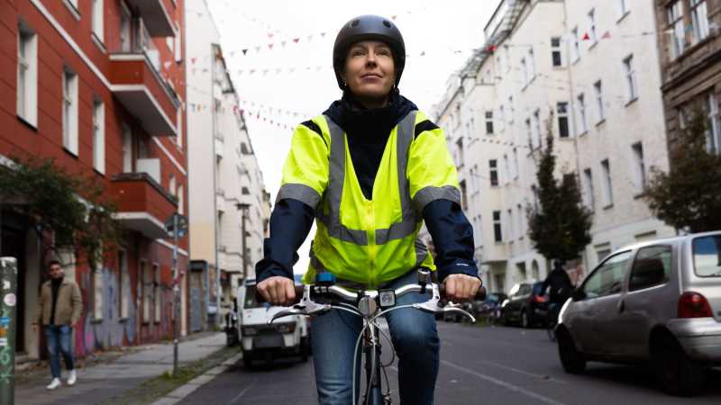 Eine Frau fährt mit dem Fahrrad auf einer Straße.