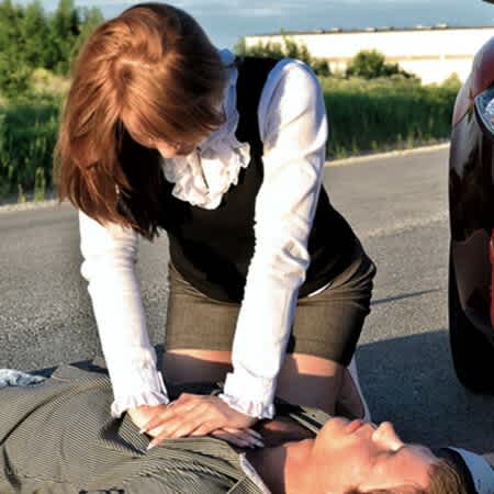 Eine Frau beugt sich über einen Mann und führt eine Herz-Druck-Massage durch.
