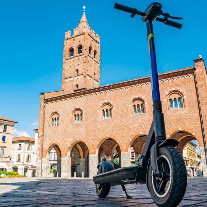 Ein E-Scooter steht auf einem Platz vor einem historischen Gebäude.
