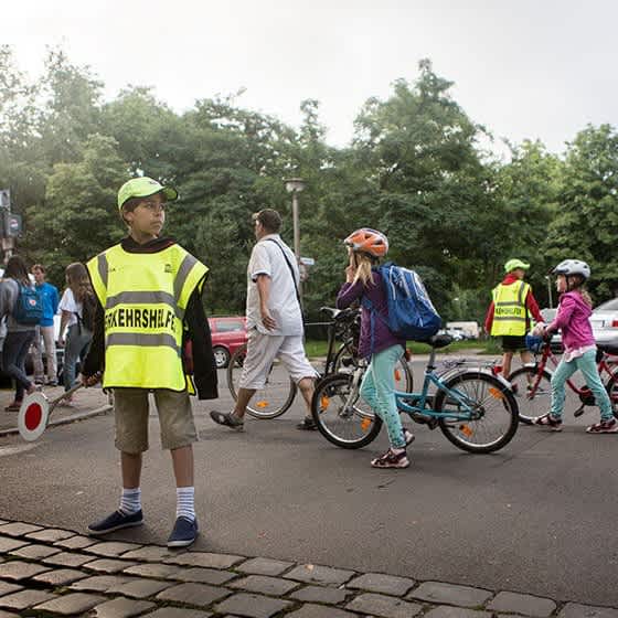 Zwei Schülerlotsen sichern den Straßenübergang, damit die Schüler die Straße sicher überqueren können.