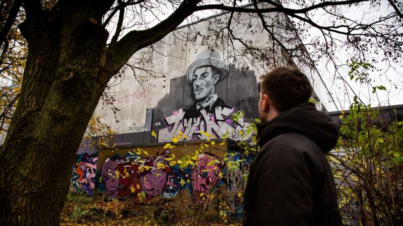 Philipp Zumhasch steht vor einem Wandgemälde seines verstorbenen Freundes Johns.