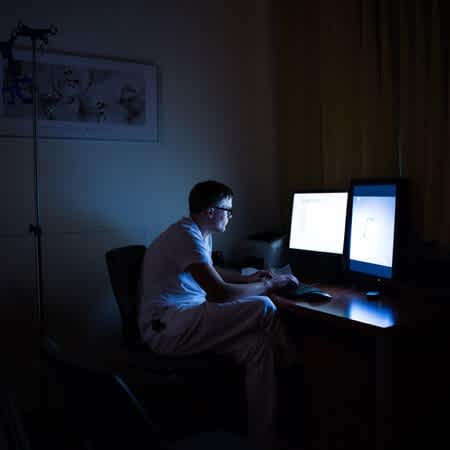 Der Arzt Florian Kunz sitzt vor einem Computer in einem abgedunkelten Raum.