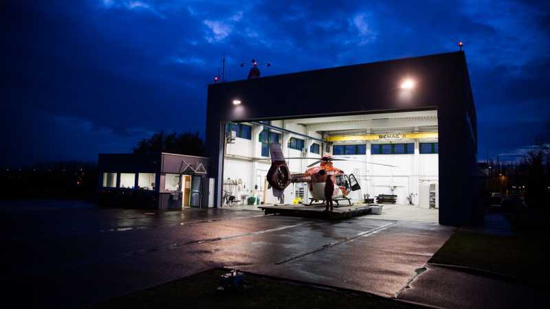 Das Bild zeigt einen Einsatz-Hubschrauber in einer Landestation. In der Dämmerung macht sich das Team bereit für den Abflug.
