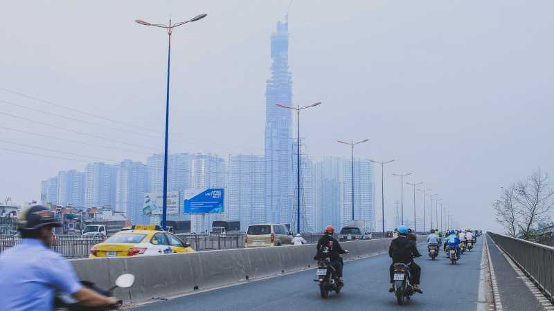 eine vielbefahrene Straße und die Wolkenkratzer von Ho Chi Minh City. 