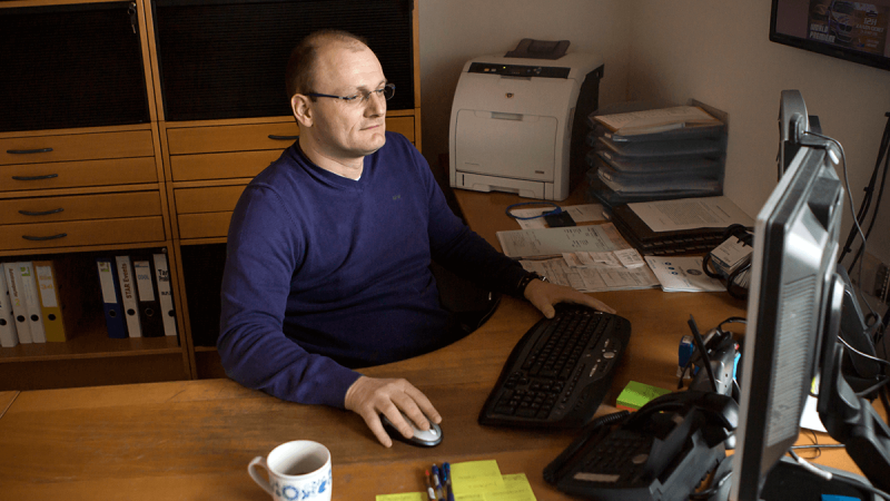 Gustav Engljähringer sitzt am Schreibtisch vor seinem Computer bei der Arbeit.