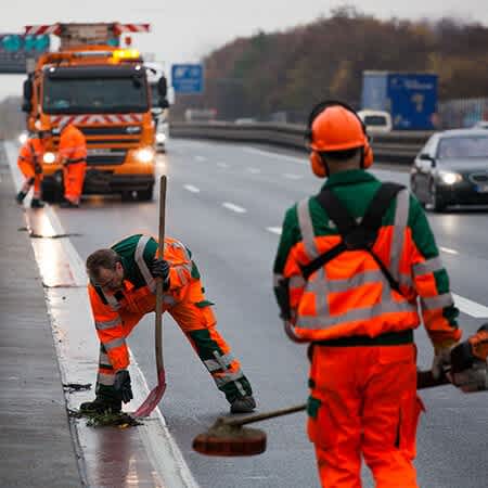 Die Straßenwärter reinigen den Seitenstreifen der Autobahn.