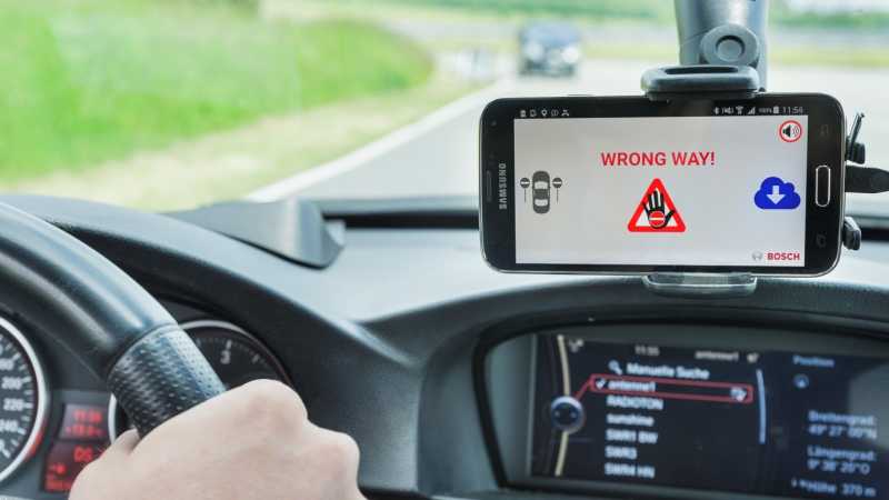 Das Display eines Smartphones zeigt eine Falschfahrerwarnung an. 