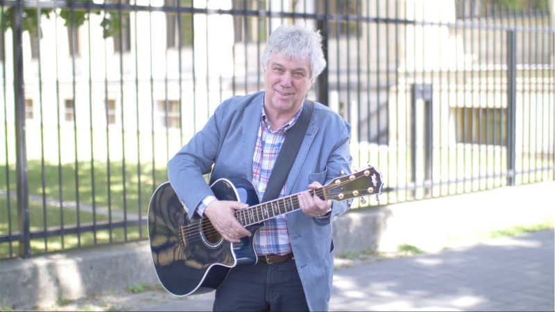 Rolf Zuckowski steht mit einer Gitarre vor dem BMVI.