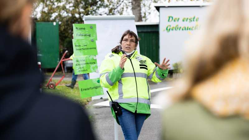 Eine Trainerin in Leuchtweste weist die Teilnehmenden des Trainings ein.