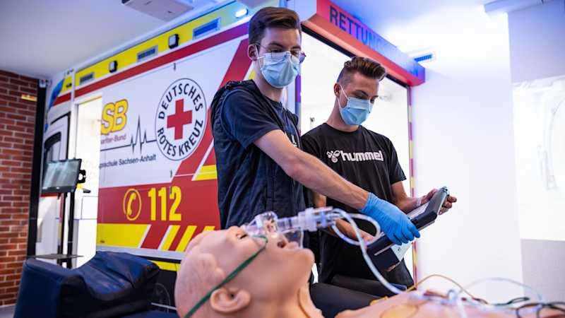 Zwei Schüler üben den Krankentransport an einem Modell. Dabei beobachten sie die Vitalwerte des Patienten. 