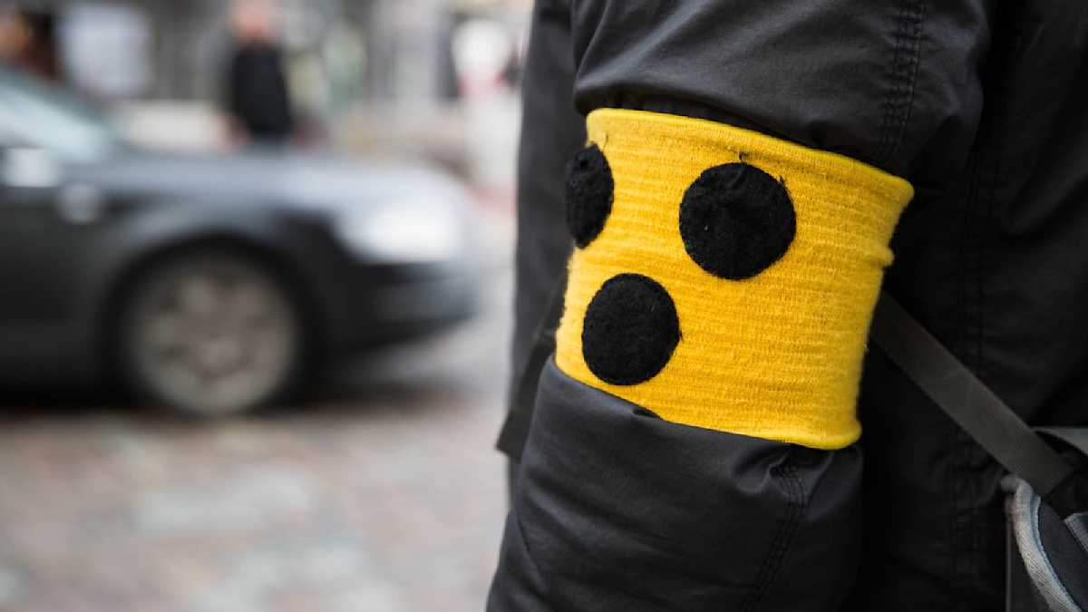 Eine Person Trägt Eine Gelbe Armbinde Mit Drei Schwarzen Punkten www.runtervomgas.de