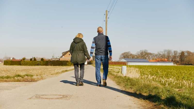 Ein Mann und seine Frau halten sich an den Händen und gehen spazieren. 