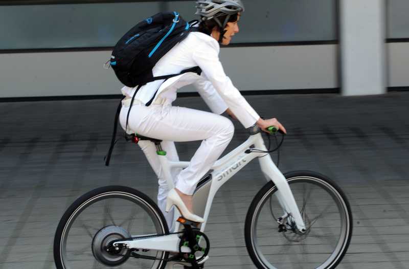 eine Frau in weiß gekleidet sitzt fährt auf einem weißen Fahrrad.
