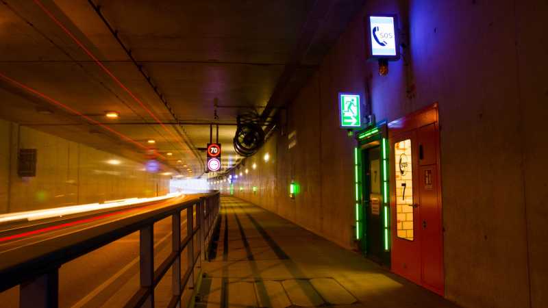 Gut gekennzeichnet: Ein grün leuchtendes Schild zeigt einen Notausgang in einem Straßentunnel an.