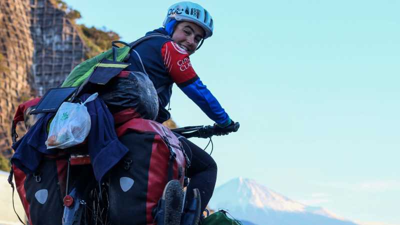 Luisa Rische sitzt auf ihrem Fahrrad, im Hintergrund sieht man den Vulkan Fuji in Japan.