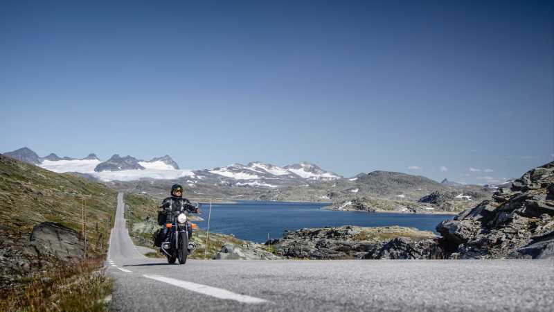 Mike Dodd fährt auf dem Motorrad auf einer Landstraße an der norwegischen Küste.