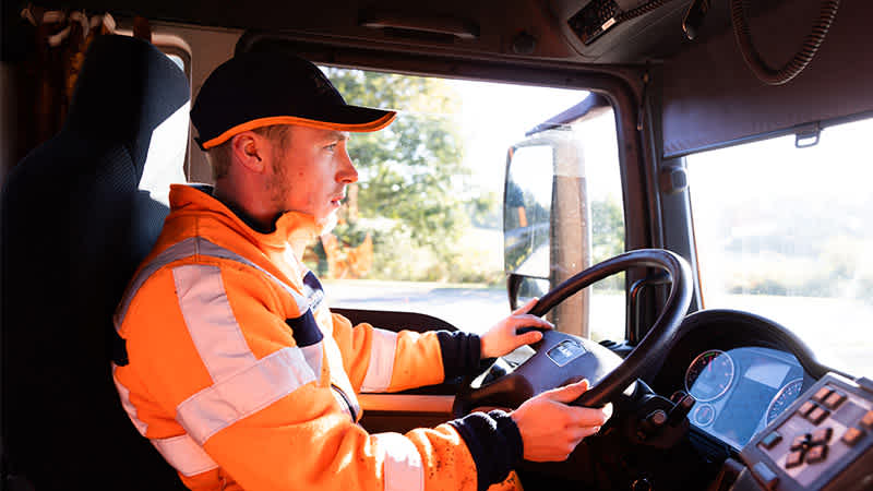 Ein Straßenwärter sitzt am Steuer eines Lkw und fährt.