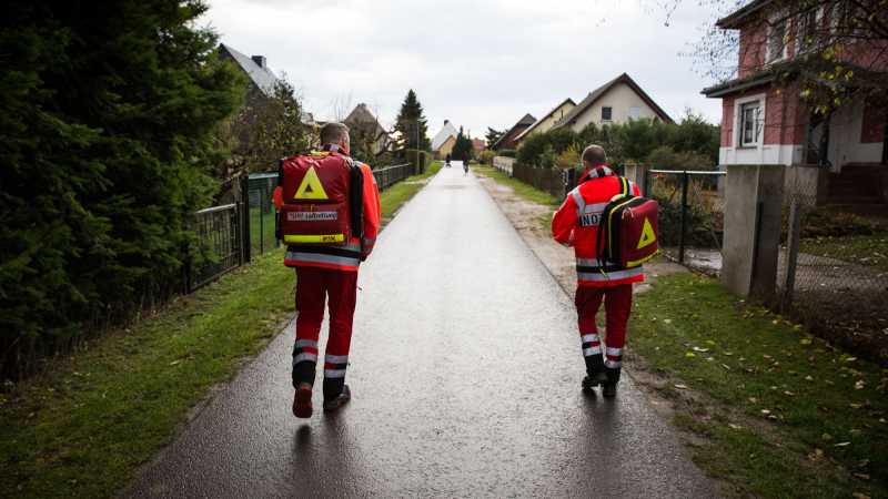Das Bild zeigt den Notfallsanitäter Thomas Scheffler und Notarzt Stefan Gerke auf einem Gehweg. Sie bedingen sich auf dem Weg zum Einsatzort.