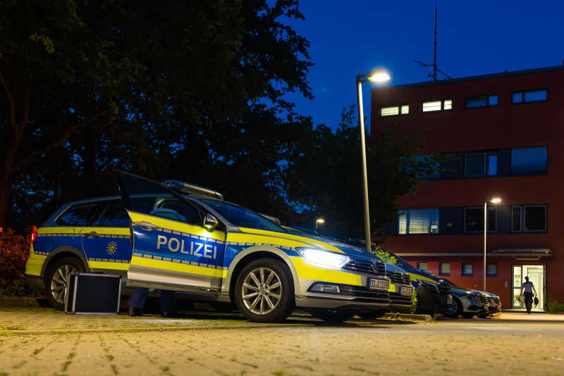 Ein Streifenwagen steht mit geöffneter Beifahrertür auf einem Parkplatz.