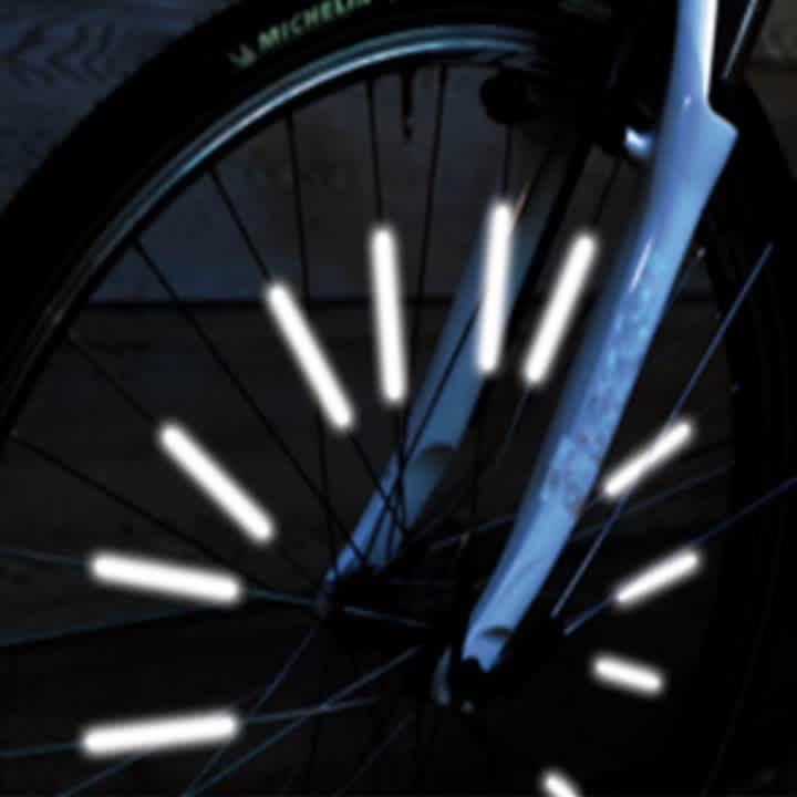 Das Bild zeigt die Nahaufnahme eines Fahrradreifens mit Reflektoren in den Speichen.