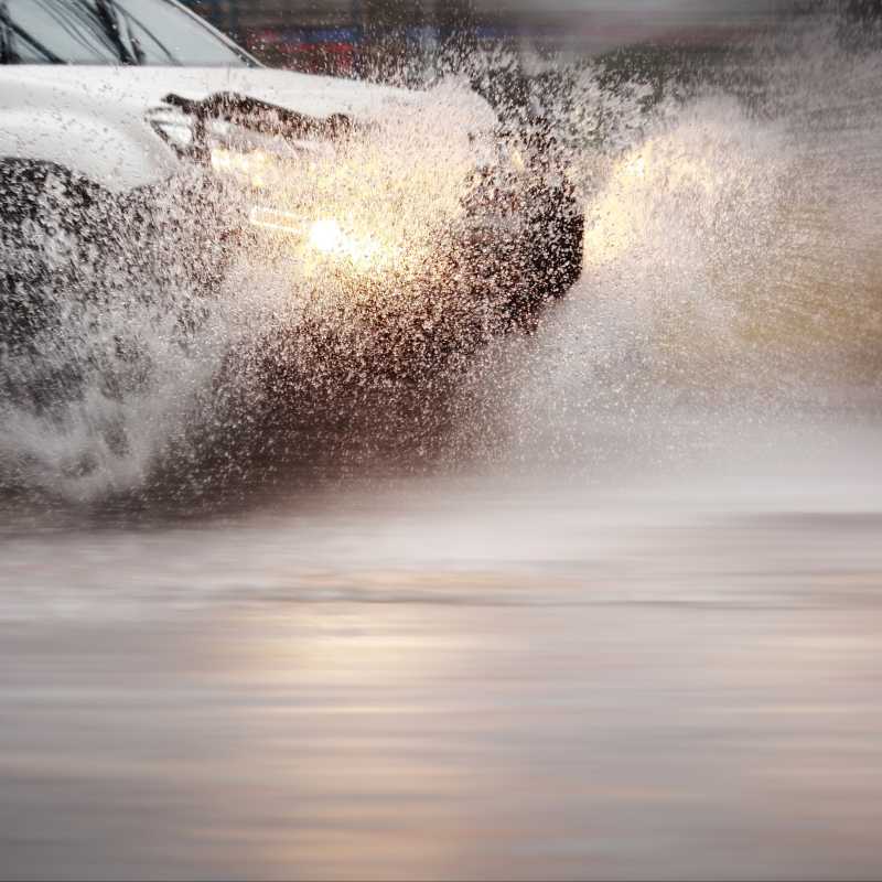 Ein weißes Auto fährt durch eine große Wassermenge.