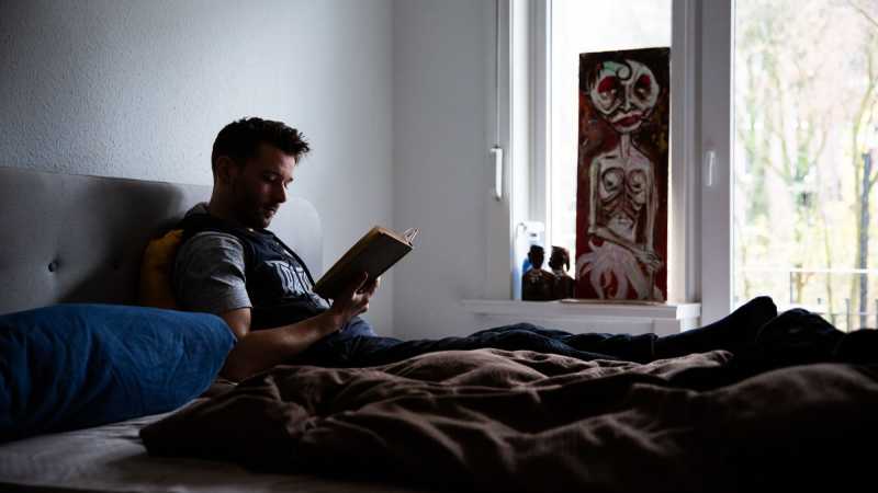 Philipp Zumhasch liegt im Bett und liest ein Buch.