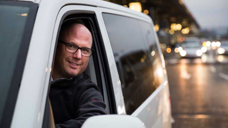 Das Bild zeigt Björn P. währende der Fahrt in seinem Auto. Er blickt der Kamera aus dem Fenster seiner Fahrerseite heraus entgegen.
