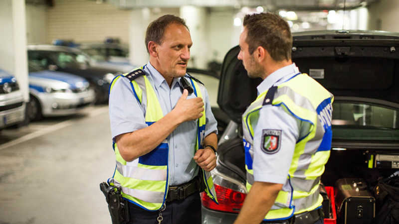 Die Polizisten Rainer Fuchs und Marco R. bereiten sich vor ihrem zivilen Einsatzwagen auf ihren Einsatz vor.