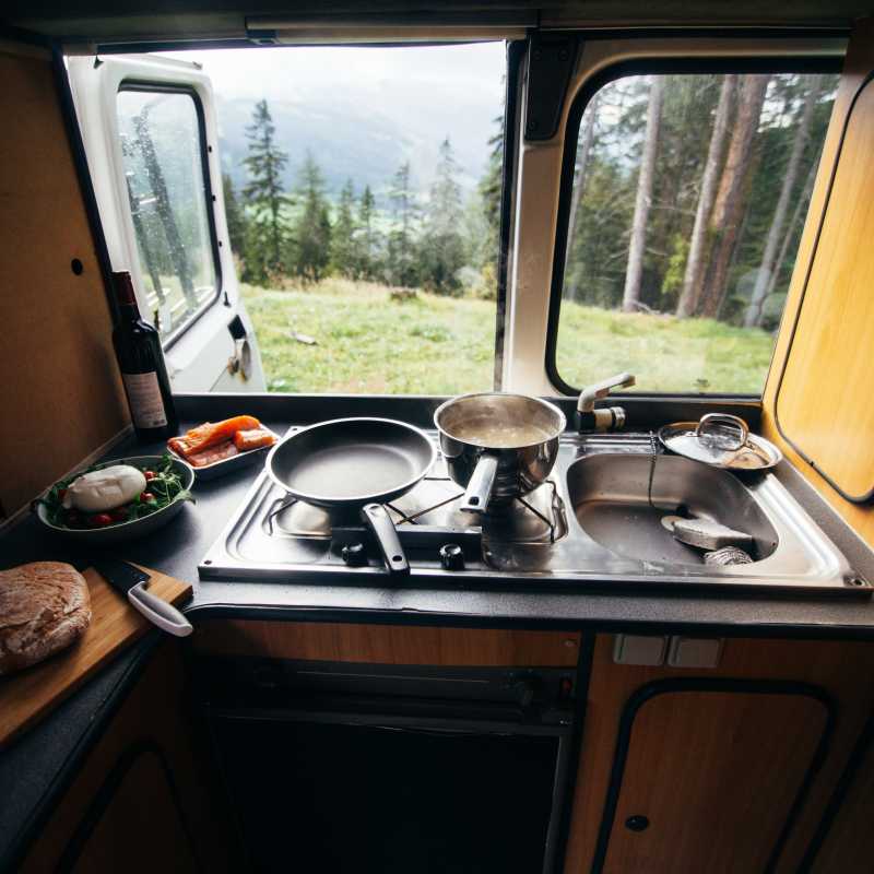 Herd und Spüle in einem Campingbus mit Blick in die Natur.