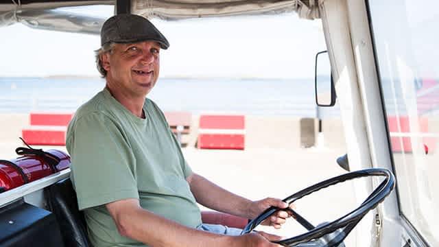Der Fahrer der Inselbahn auf Helgoland Bert sitzt am Steuer der Inselbahn und lächelt in die Kamera.
