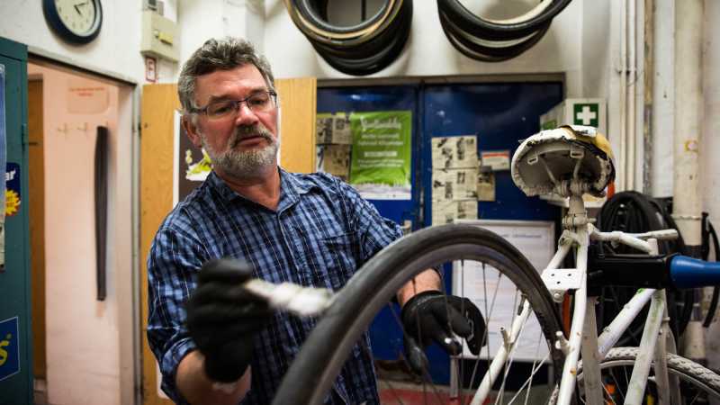 Ein Mann malt ein Fahrrad weiß an.