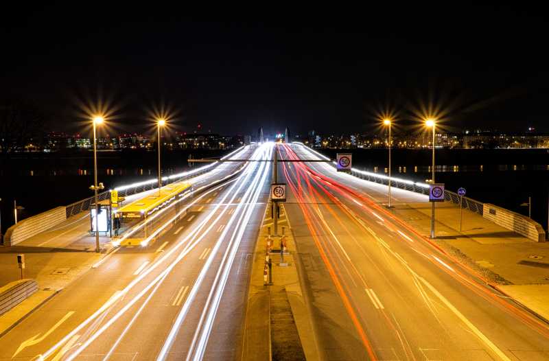Das Bild zeigt Straßenverkehr bei Nacht, die Lichter verschwimmen. 