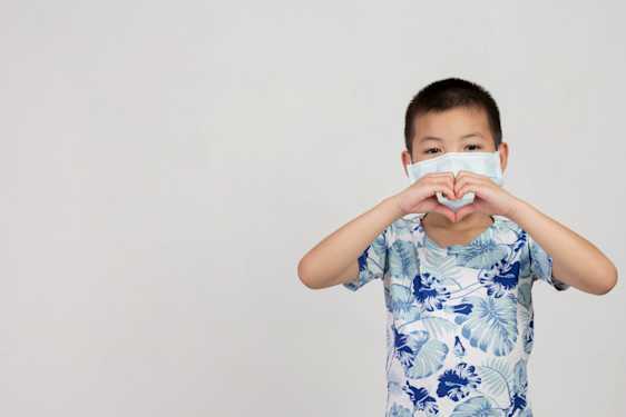 niño usando mascarilla haciendo un corazón con sus manos