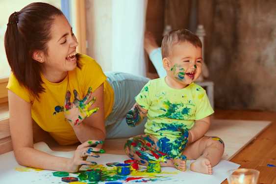 Bebé y mujer riendo, pintando y ensuciándose con pintura